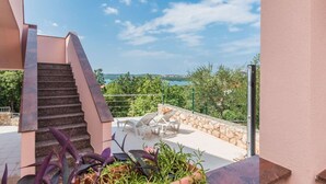 Un espace extérieur moderne doté d’un escalier menant à une terrasse, d’un espace piscine avec des chaises longues et d’une vue sur la mer.