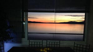 A room with a large window overlooking a calm body of water at sunset. - Wohnung Fiorino Rijeka, Kvarner Bucht by Interhome (Rijeka)