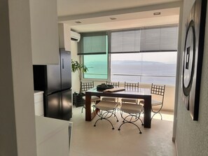 A modern kitchen with a built-in refrigerator, a dining area with a table and chairs, and a large window offering a view of the sea. - Wohnung Fiorino Rijeka, Kvarner Bucht by Interhome (Rijeka)
