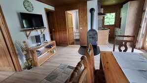 Ein gemütliches Wohnzimmer mit Holzvertäfelung, Kamin, Fernseher und Bücherregal.