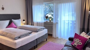 A bedroom with a bed, a nightstand, a lamp, a window with curtains, and a view of the outdoors. - Haus Rosenwirth by Interhome (Mittenwald)