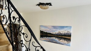A wooden staircase with black wrought iron railings, a wall-mounted picture of a mountain lake, and a ceiling light fixture. - Haus Rosenwirth by Interhome (Mittenwald)