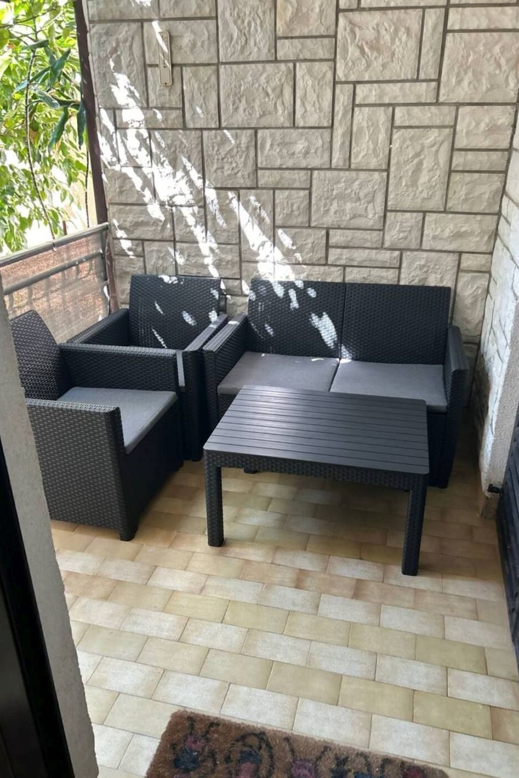 Un espace patio agrémenté d’un mur en pierre, d’un canapé de couleur foncée et d’une table assortie.