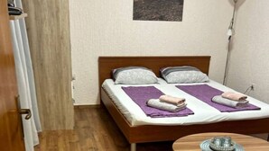 A small, cozy room with a wooden floor, a bed with purple bedding, a small round table with a decorative item, and a gray sofa. - Villa Hanka App.Piccolo, Balkon bis 3 Pers. EG by Interhome (Umag)