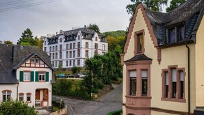 Una calle con arquitectura tradicional europea, incluyendo un edificio con tejado a dos aguas y otro con ventanal saliente.
