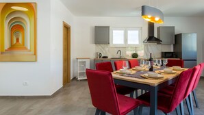 Een moderne eetruimte met een lange tafel, rode stoelen en een hanglamp.