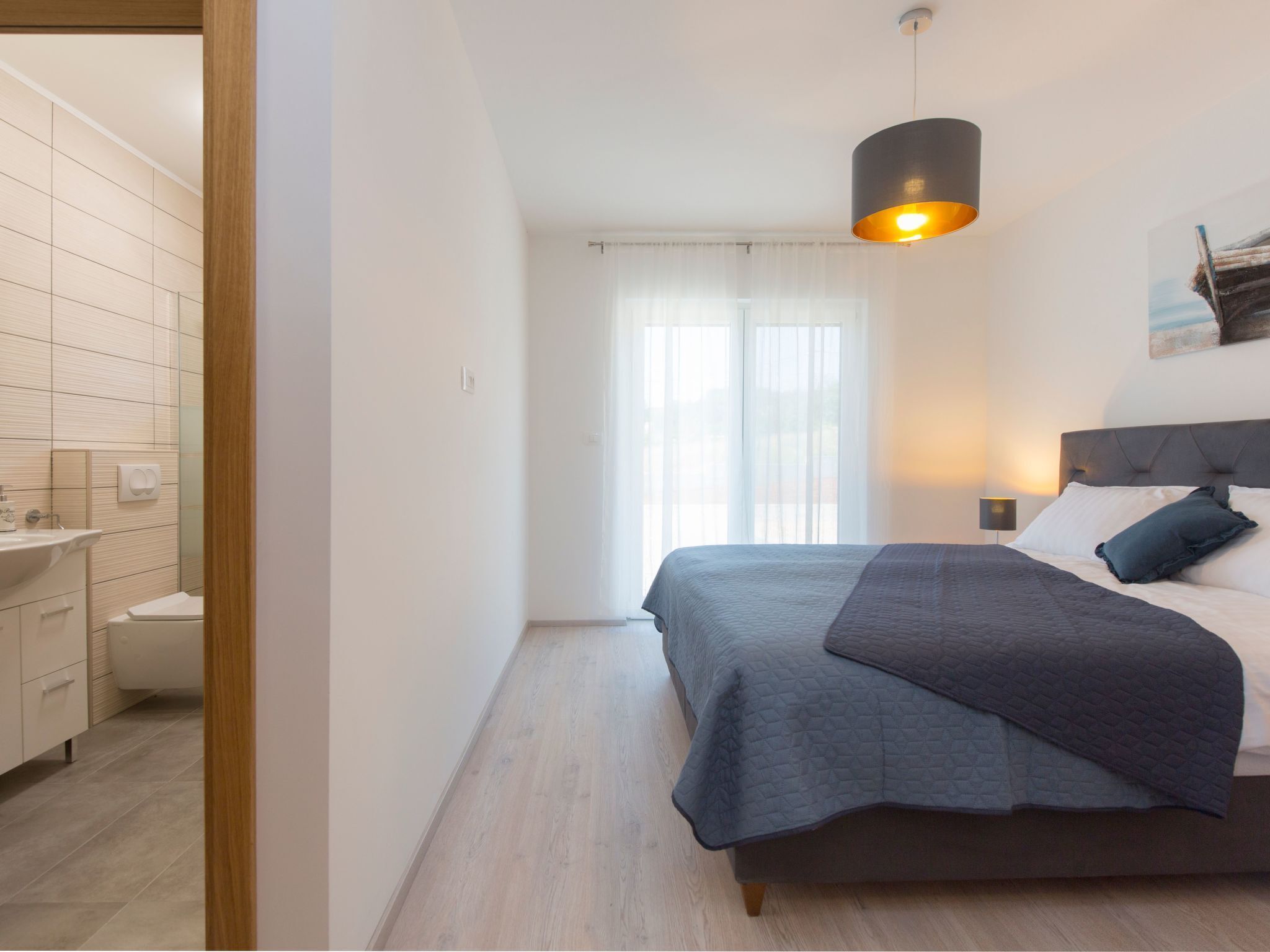 Quarto moderno com cama, mesa de cabeceira e janela com cortinas.