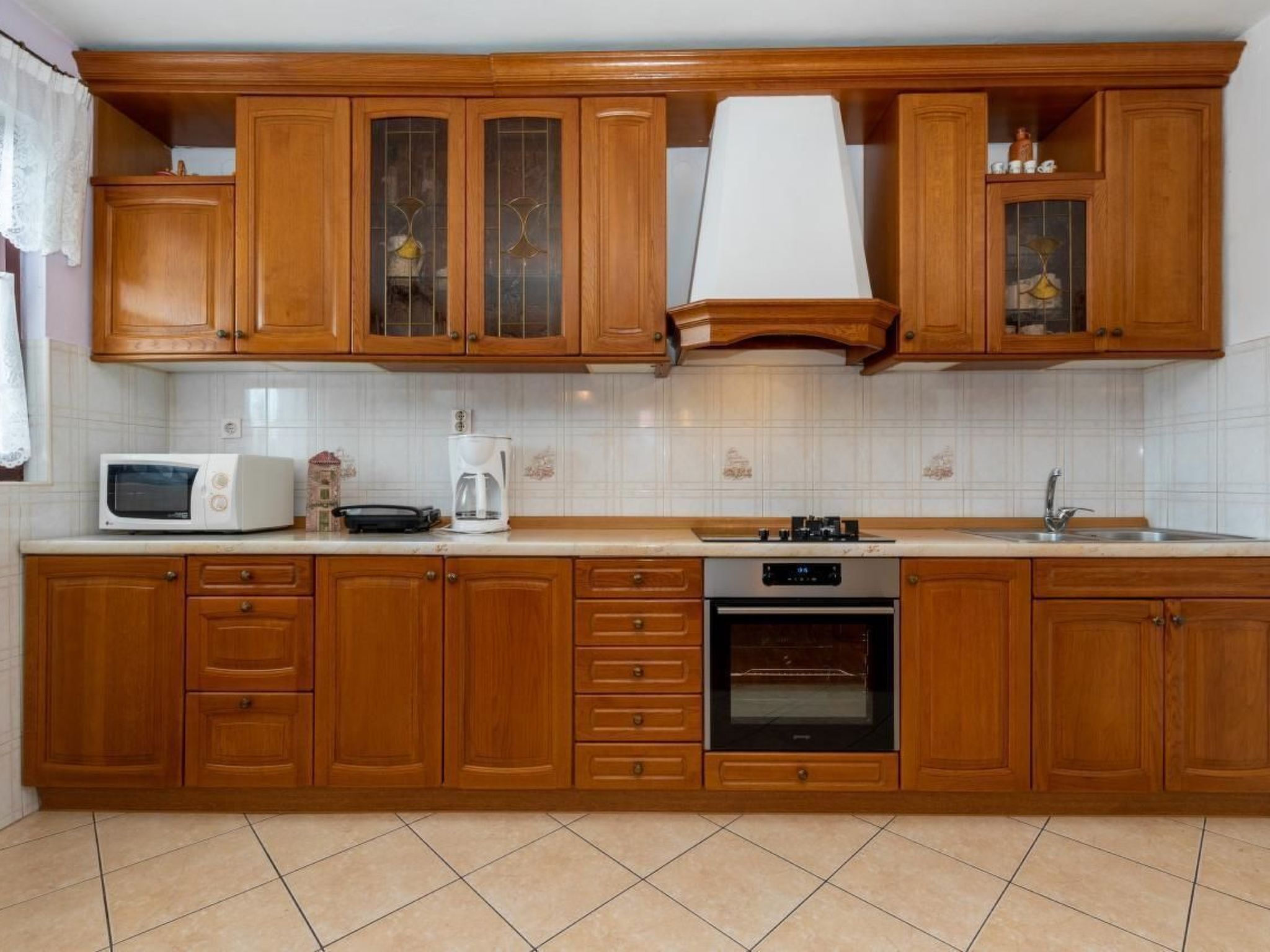 A kitchen with wooden cabinets, a microwave, a coffee maker, a stove, and a sink.