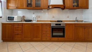 Una cocina con armarios de madera, microondas, cafetera, estufa y fregadero.
