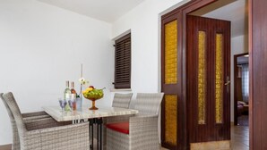Un comedor con sillas de mimbre, una mesa con frutero y una puerta de madera con detalles dorados.