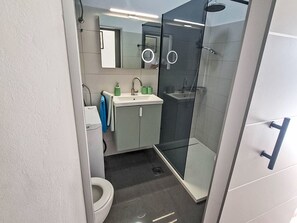 A modern bathroom with a toilet, sink, mirror, and glass shower enclosure. - für 4 Personen  + 1 Kind ca. 95 m² in Pula, Istrien (Pula und Umgebung) by Interhome (Pula)
