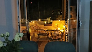 A balcony with wicker furniture and a potted plant, overlooking a street at night. - Summer escape Rovinj by Interhome (Rovinj)
