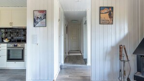 Une cuisine moderne avec des meubles blancs, un plan de travail noir et un four encastré. On peut voir une affiche accrochée au mur, et une cheminée est visible au premier plan.