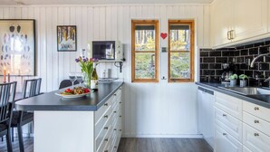 Une cuisine avec des meubles blancs, un plan de travail noir et une porte en bois ornée d’un motif en forme de cœur.