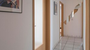 Un pasillo con suelo de baldosas, puertas de madera y una escalera de diseño único.