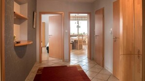 Un pasillo con alfombra roja, puertas de madera y suelo de baldosas.