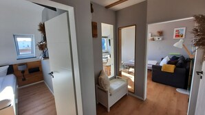 Um interior moderno com piso de madeira, um sofá branco, um sofá preto e uma área de jantar com mesa e cadeiras.