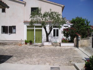 Ein Gebäude mit einem gepflasterten Innenhof, einem Baum und Kübelpflanzen.