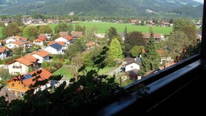 Een woongebied met huizen, groene velden en bergen op de achtergrond.