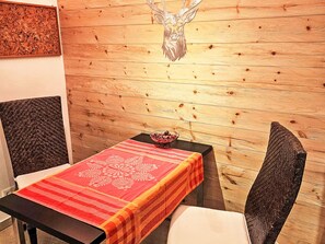 A wooden wall with a deer head decoration, a table with a patterned tablecloth, and a woven chair. - Gottschlicht by Interhome (Rottach-Egern)