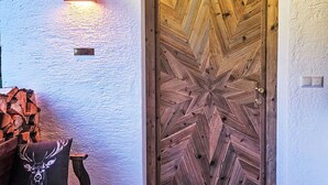 Eine Holztür mit geometrischem Muster, eine Wandleuchte und ein Kissen mit einem Hirschmotiv.