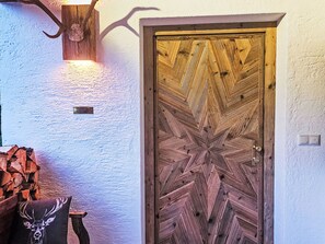 A wooden door with a geometric pattern, a wall-mounted light fixture, and a cushion with a deer design. - Gottschlicht by Interhome (Rottach-Egern)