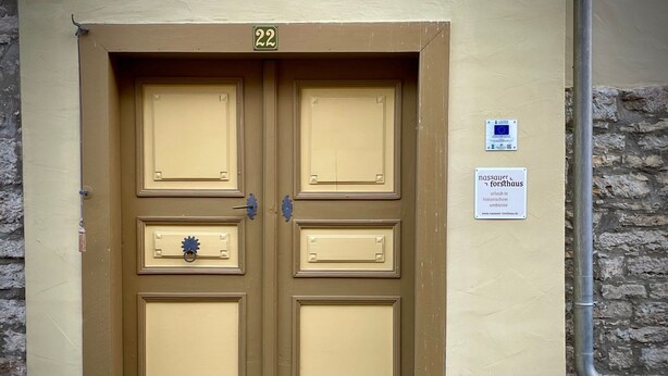 Kaksin kerroin olevat ovet, joiden yläpuolella on numero 22, pieni laatta seinässä oikealla puolella ja kiviseinä vasemmalla puolella.