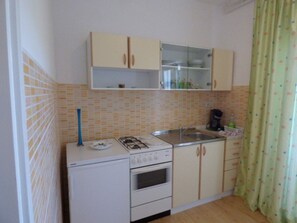 Een koelkast, een oven, kookgerei, borden en bestek