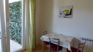 Un comedor con una mesa y sillas, una ventana con cortinas y un radiador en la pared.