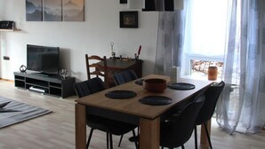 A modern living room with a wooden dining table, black chairs, a flat-screen TV, and a painting on the wall. - Wunderschön Wohnen in Weinheim by Interhome (Weinheim)