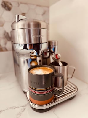 A Nespresso coffee machine with a cup of coffee on a saucer.