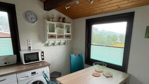 Eine kompakte Küche mit Waschmaschine, Mikrowelle und einem Essbereich mit Tisch und Stühlen.