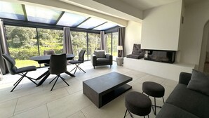 A modern living room with a glass ceiling, a fireplace, and a view of greenery. - Villa for 6 people with pool, just steps from the Golf de Valcros, in La Londe-Les-Maures (LA LONDE LES MAURES)