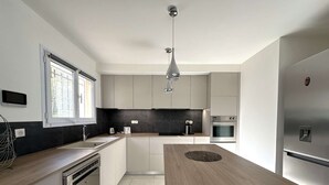 A modern kitchen with a central island, stainless steel appliances, and a pendant light. - Villa for 6 people with pool, just steps from the Golf de Valcros, in La Londe-Les-Maures (LA LONDE LES MAURES)