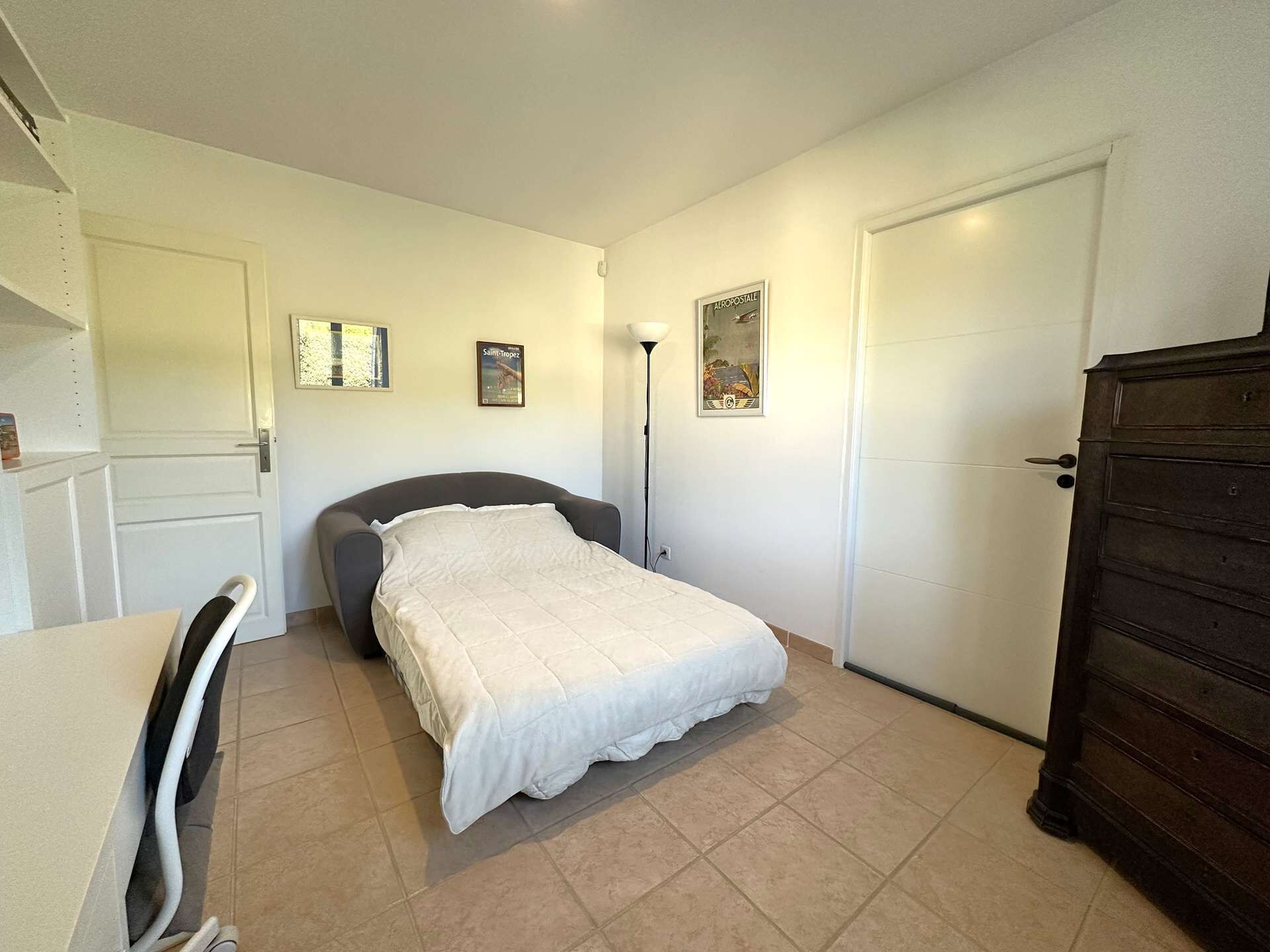 Une chambre à coucher avec un lit, un bureau, une chaise, une armoire et une porte.
