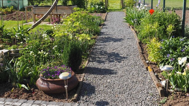 A garden pathway leading to a wooden archway, surrounded by various plants and flowers. - Hochwertige Ferienwohnung mit Terrasse und Garten by Interhome (Zülpich)