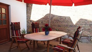 An outdoor patio with a round wooden table, four chairs, and a red umbrella. - Hochwertige Ferienwohnung mit Terrasse und Garten by Interhome (Zülpich)