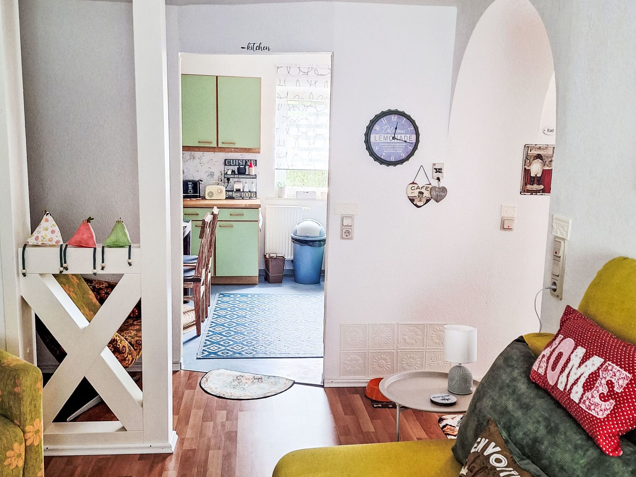 Ein Wohnzimmer mit einer Couch, einem Couchtisch und einer durch eine offene Tür sichtbaren Küche.