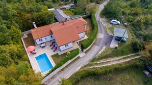 An aerial view of a house with a swimming pool, surrounded by lush greenery and a winding road. - Haus Mia by Interhome (Labin)
