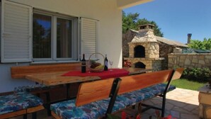 An outdoor patio with wooden benches and a stone fireplace. - Haus Mia by Interhome (Labin)