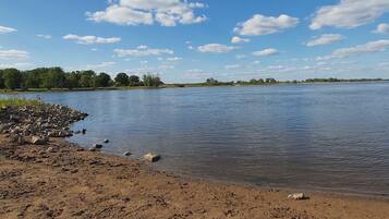 A riverbank with a rocky shoreline and trees in the background.