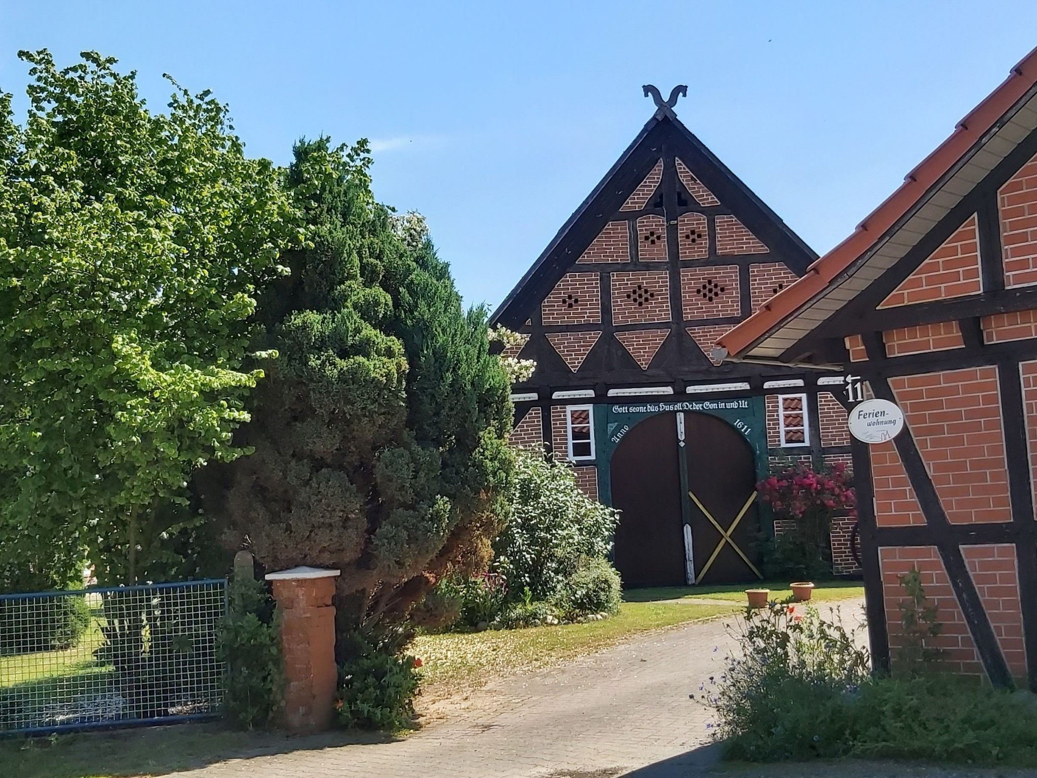 A traditional half-timbered building with a prominent entrance, a sign indicating a restaurant, and a fenced garden area.