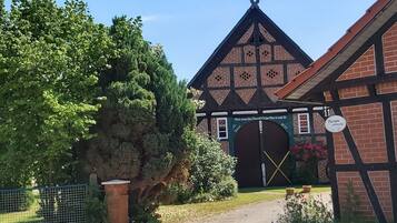 A traditional half-timbered building with a prominent entrance, a sign indicating a restaurant, and a fenced garden area.