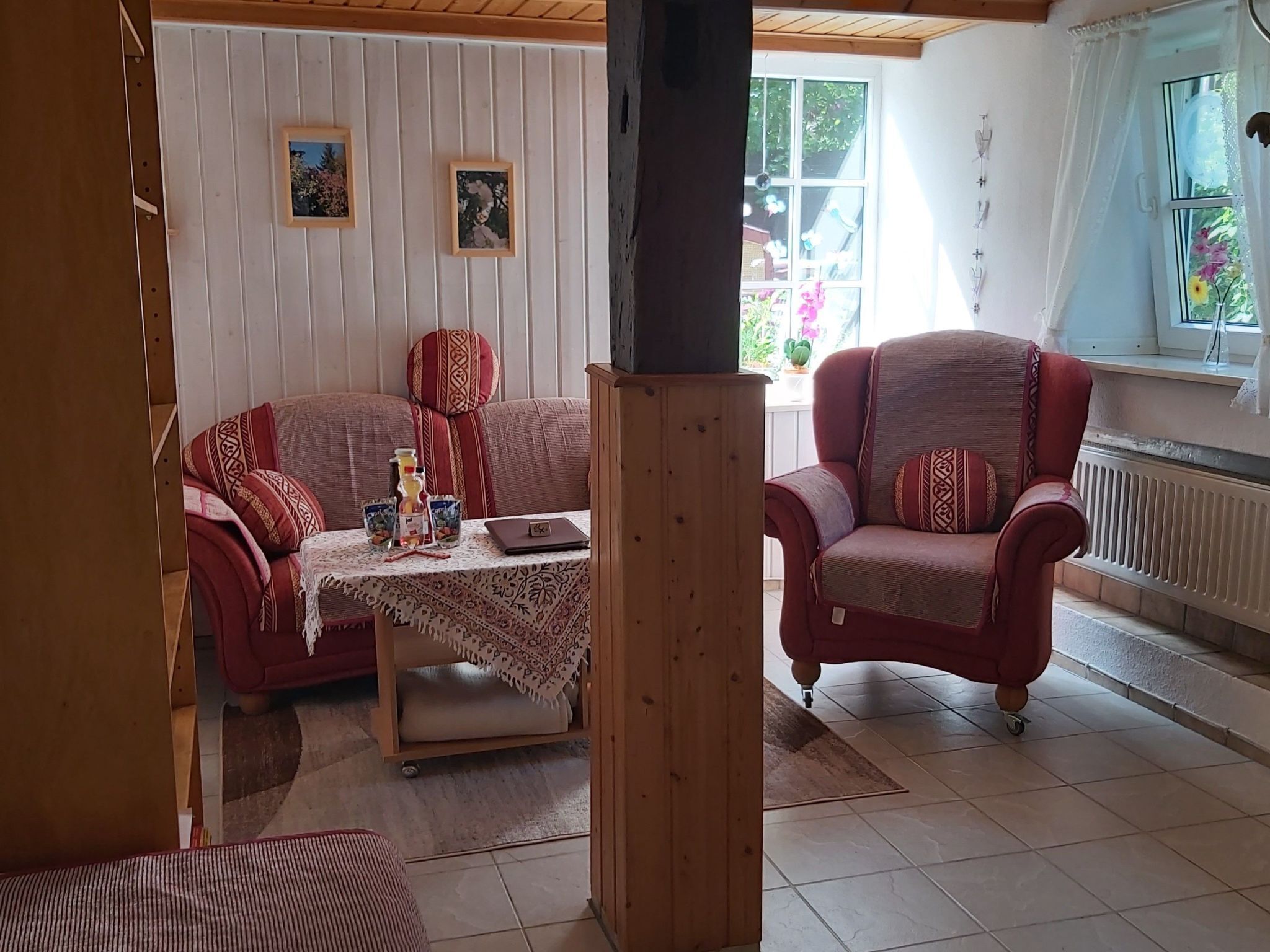 A cozy living room with a sofa, armchair, and a small table with a laptop.