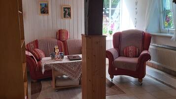 A cozy living room with a sofa, armchair, and a small table with a laptop.