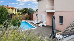 A backyard with a swimming pool, lounge chairs, and a covered patio area. - mit Blick auf das Wasser by Interhome (Labin)