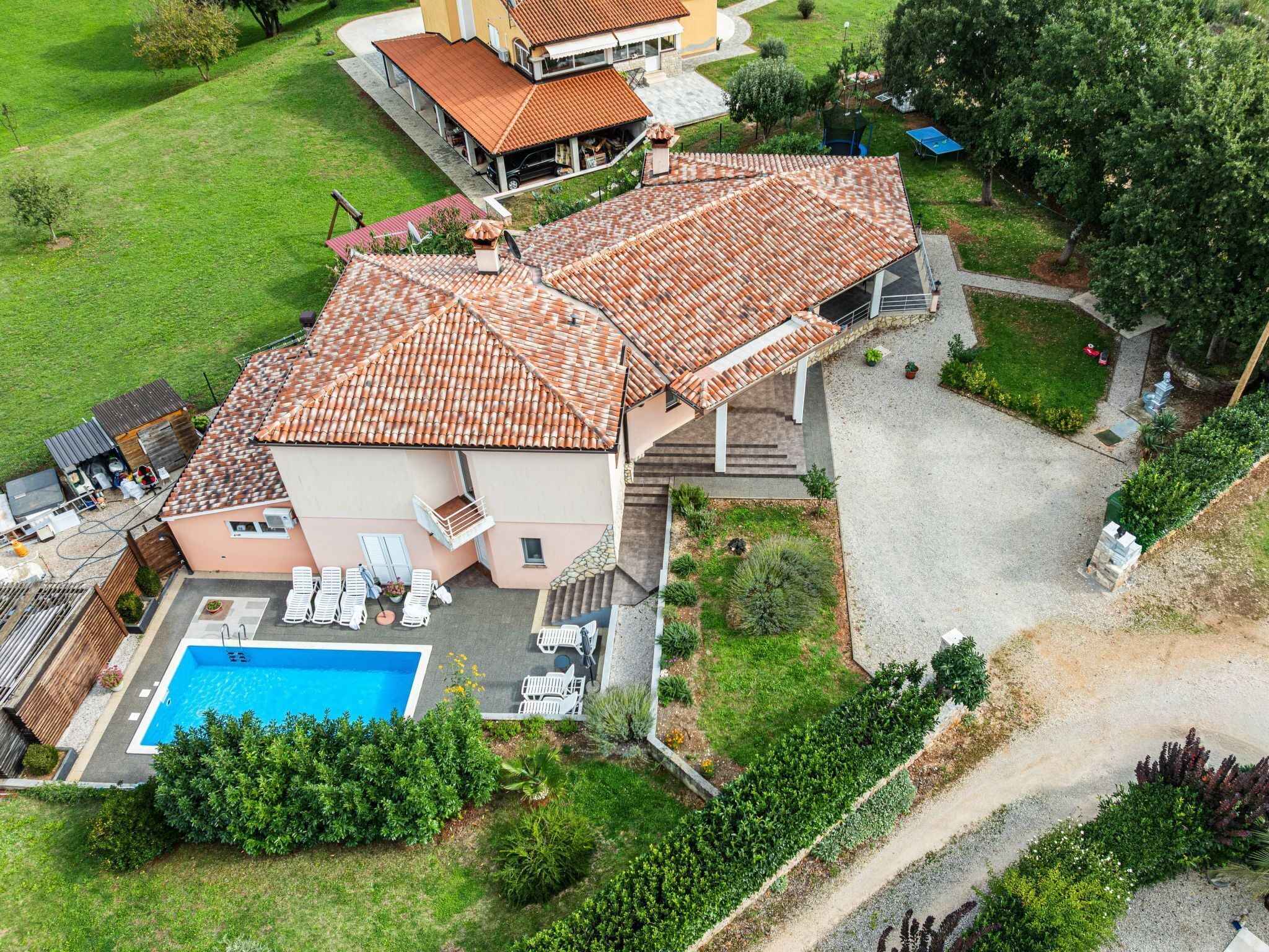 Vue aérienne d’une maison avec une piscine, un patio couvert et un jardin.