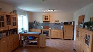 Keittiössä on puiset kaapit, ruokapöytä ja mikroaaltouuni.