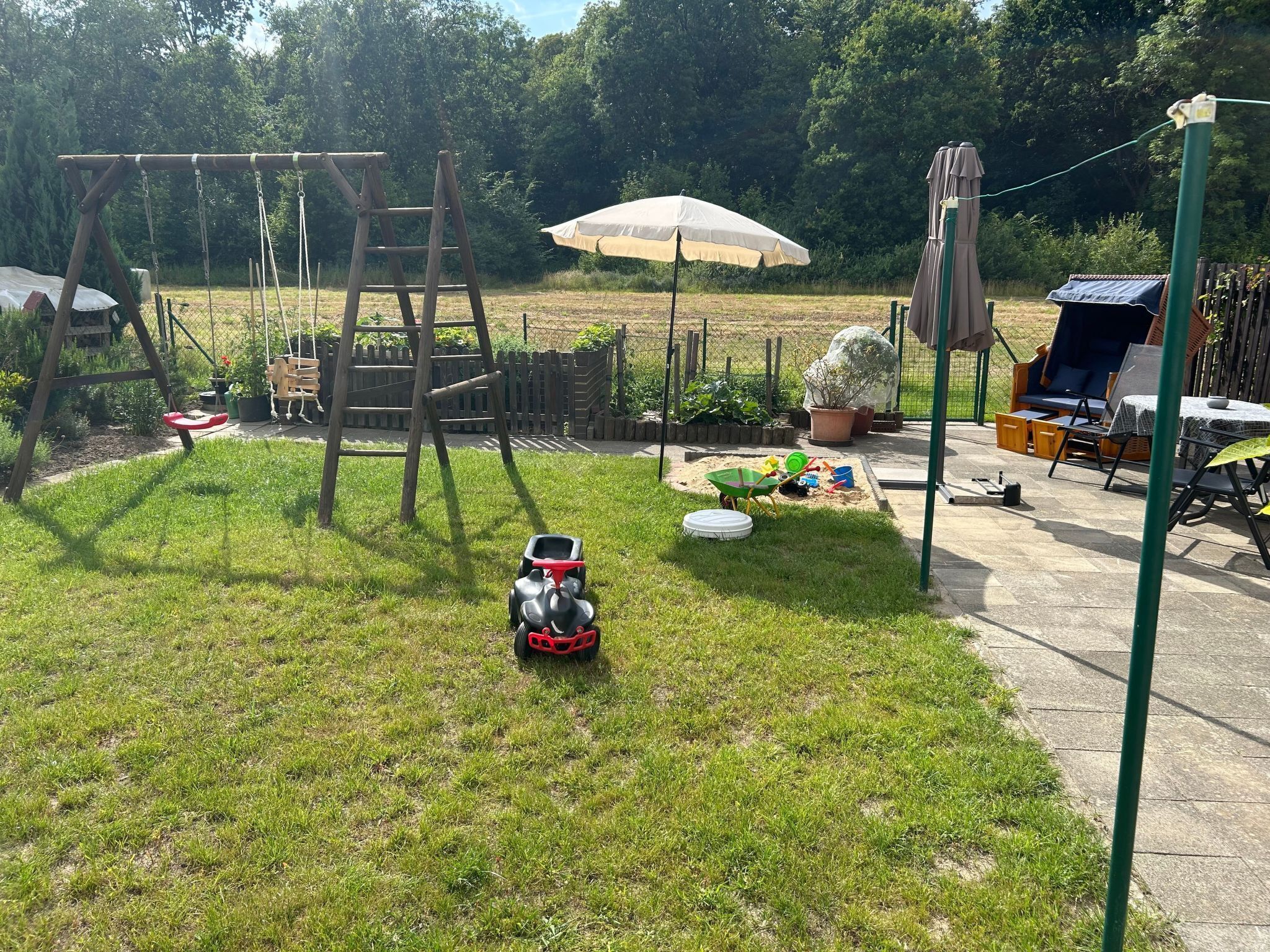 A backyard with a swing set, a small play area, and a garden.