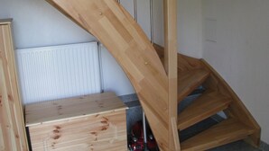 A wooden staircase with a handrail, a radiator, and a small wooden chest of drawers. - Appartement in Steinhude mit Grill by Interhome (Wunstorf)